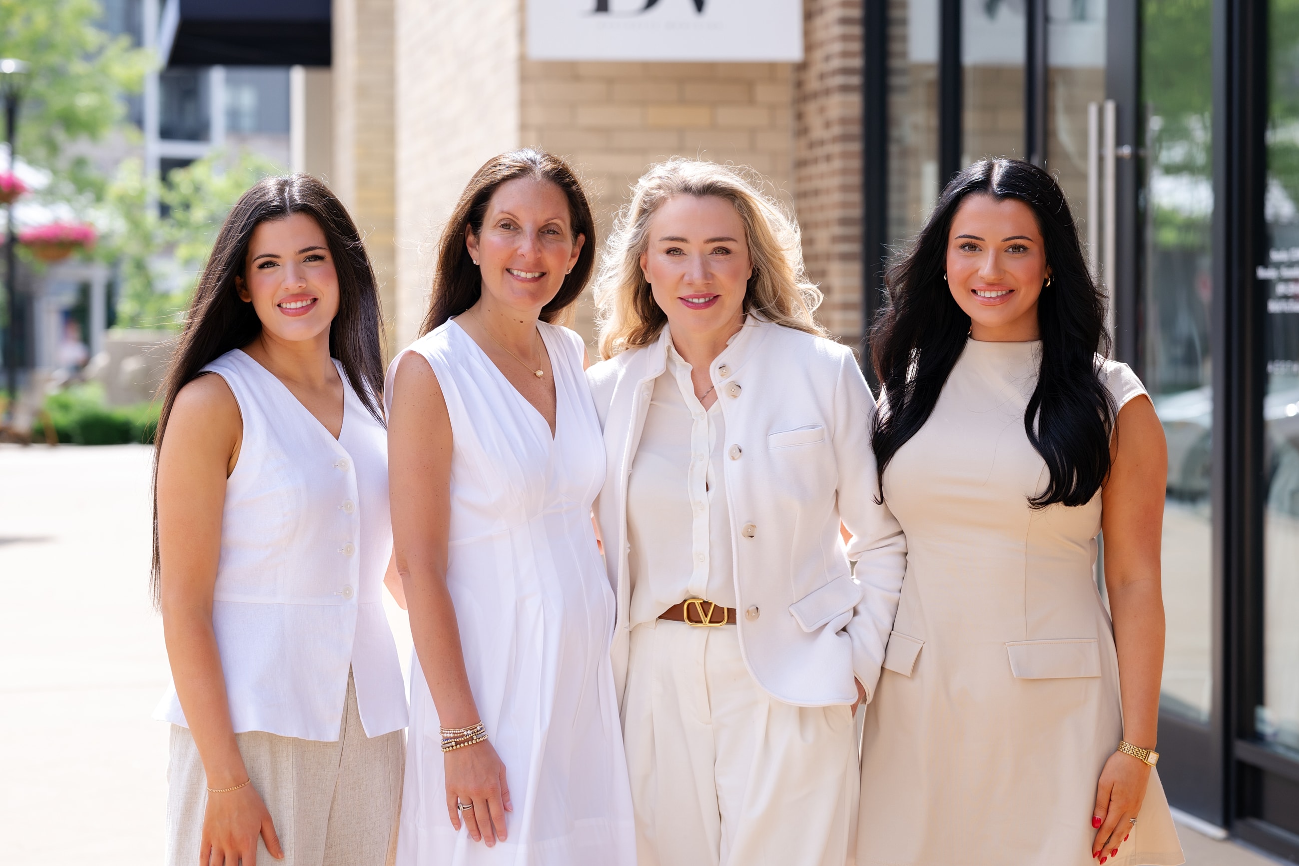 Four women posing outdoors in stylish outfits.
