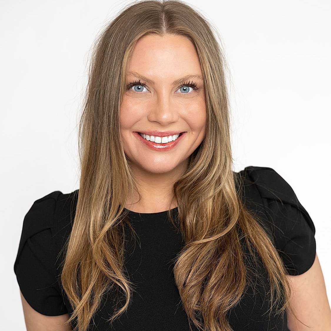 Smiling woman with long hair in black dress.