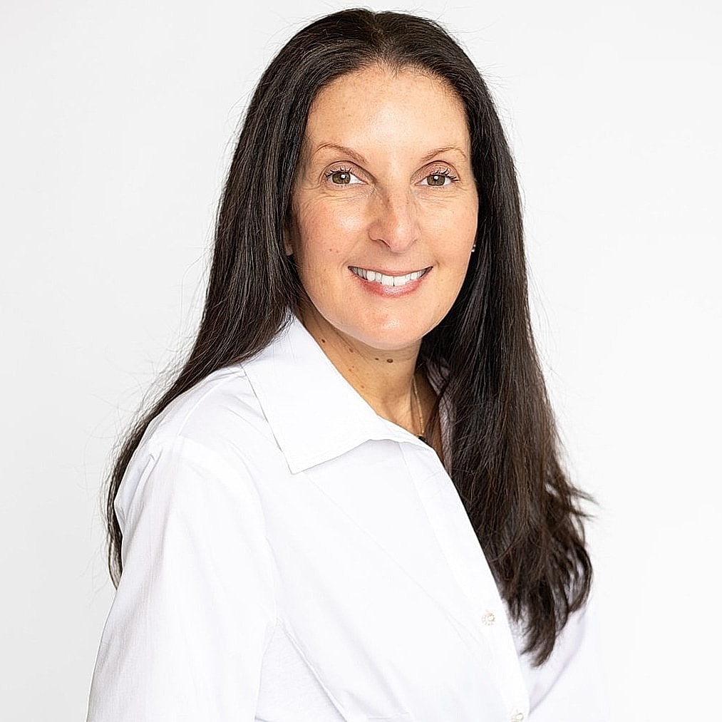 Smiling woman in white shirt against white background.