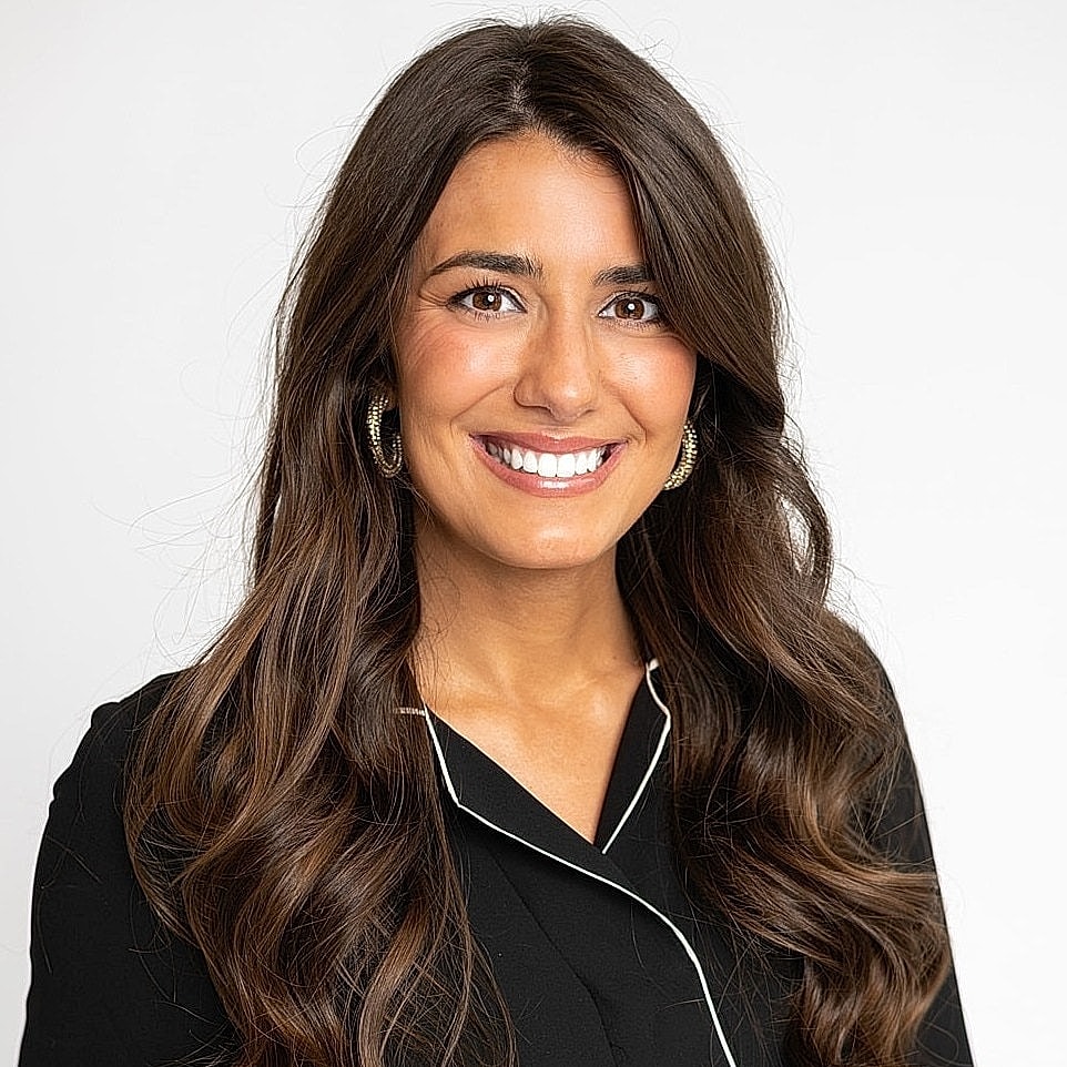 Smiling woman in a black blouse, light background.