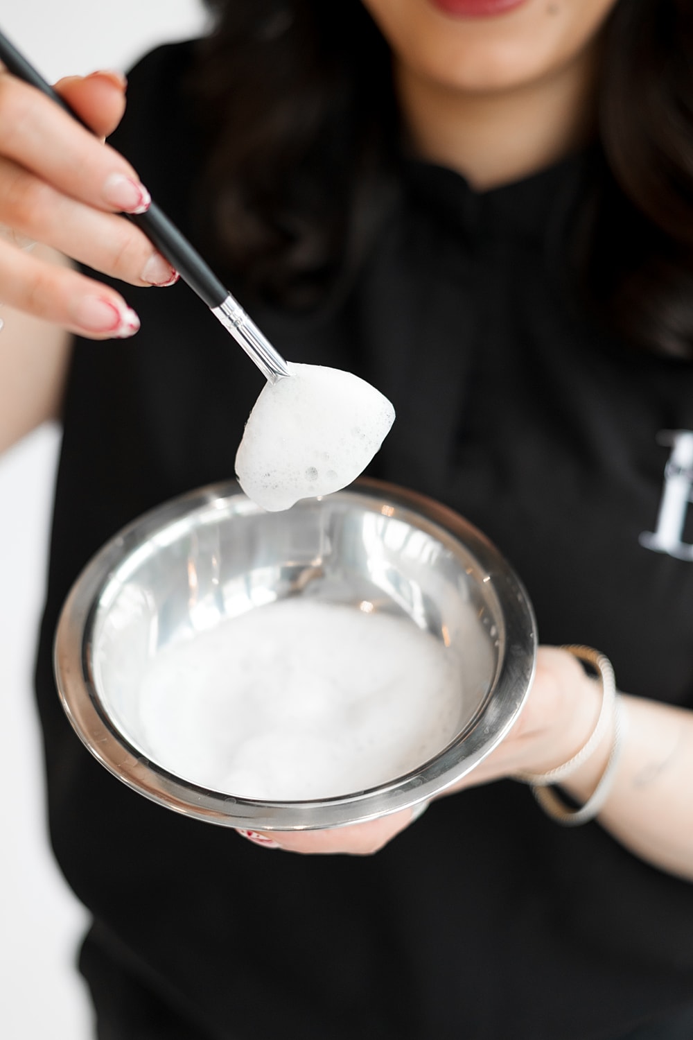 Woman holding bowl of foamy mixture.