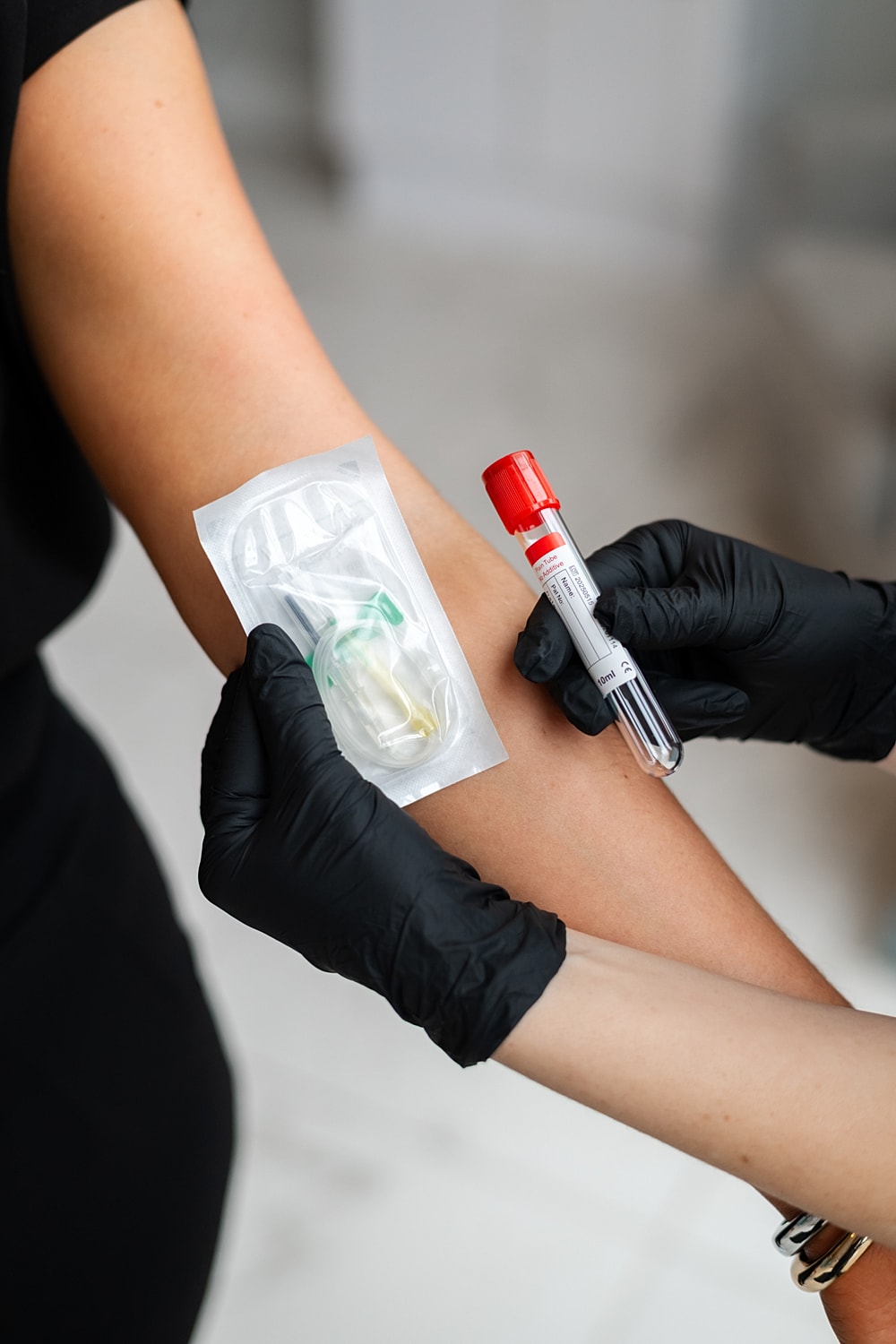 Blood test procedure with gloved hands.