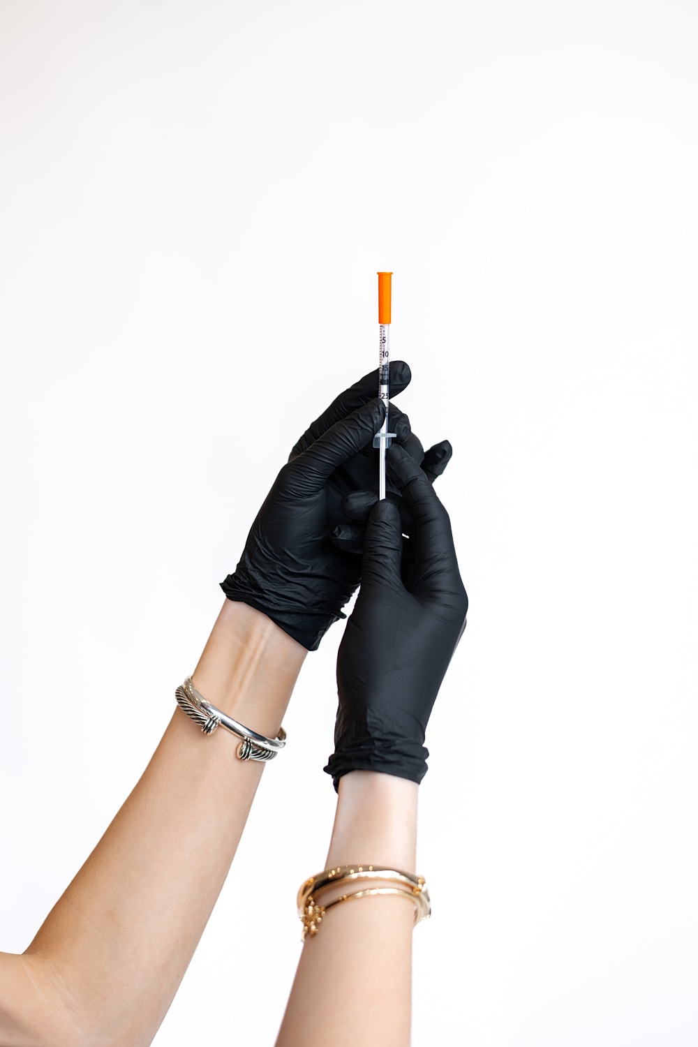 Person holding a syringe in gloved hands.