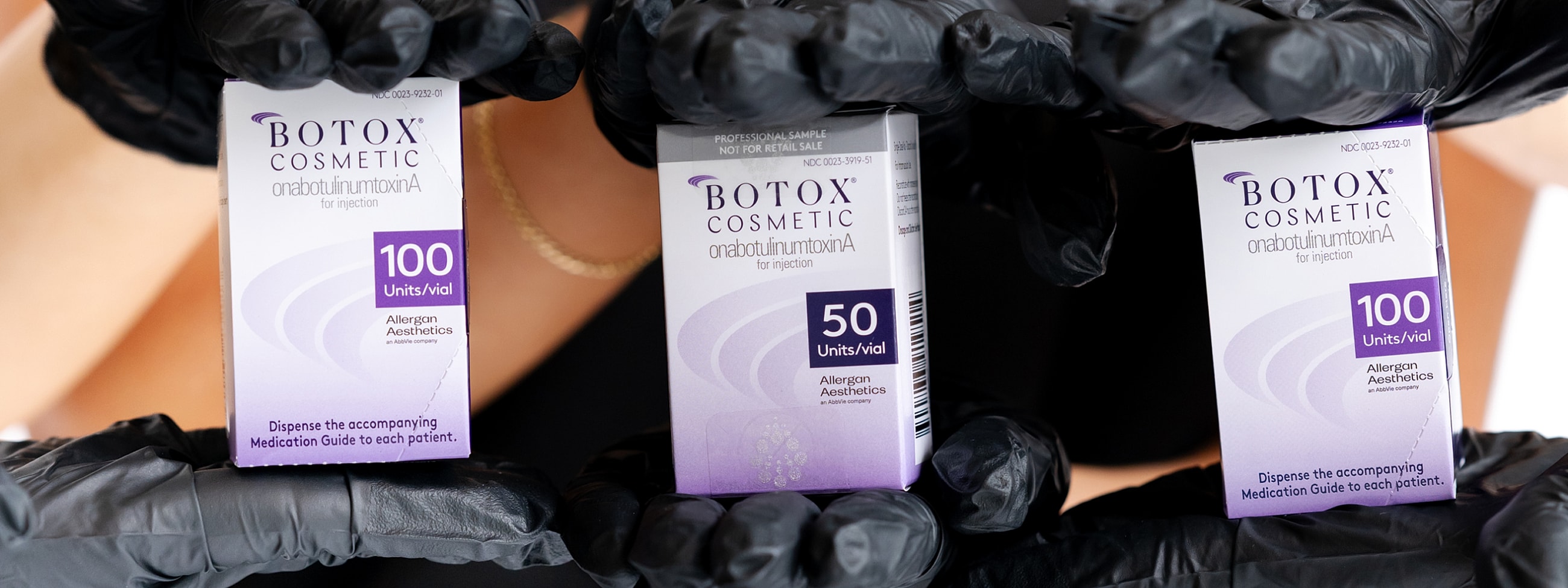 Botox vials held by gloved hands for injection.