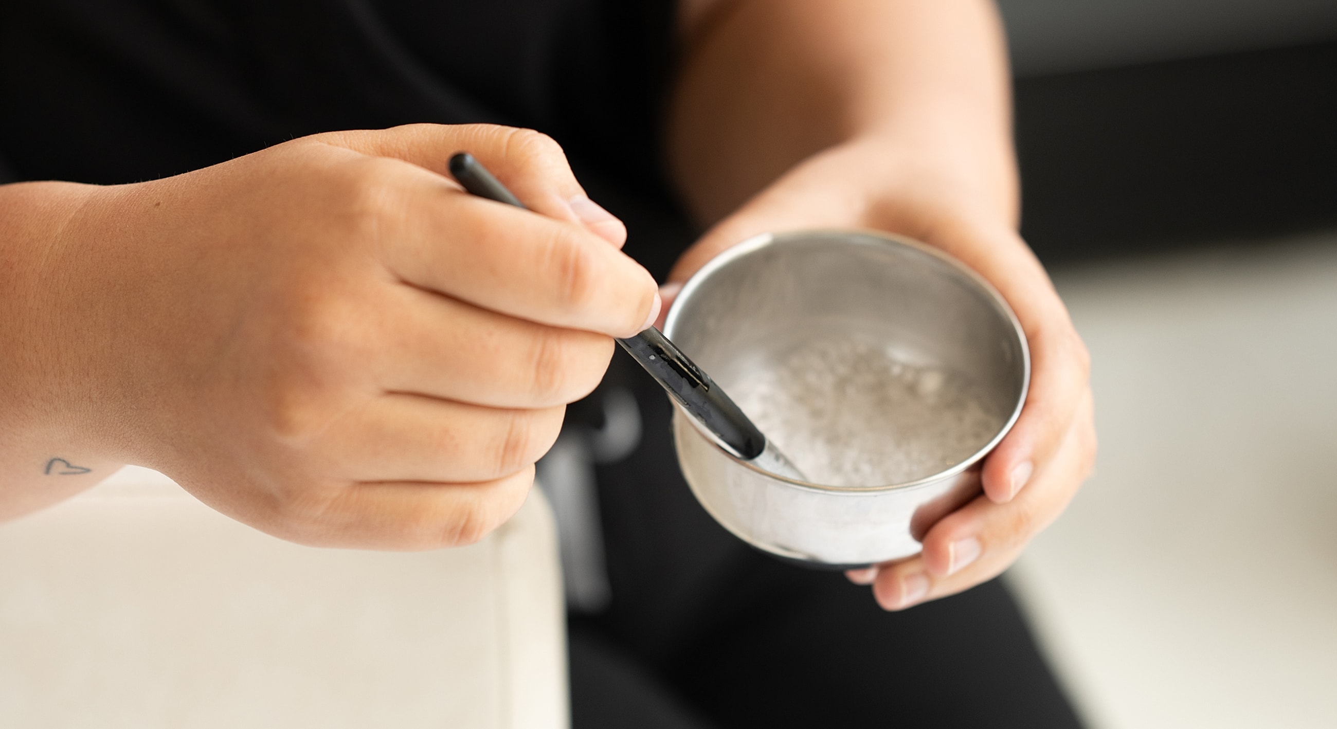 Person stirring a bowl with a small spoon.