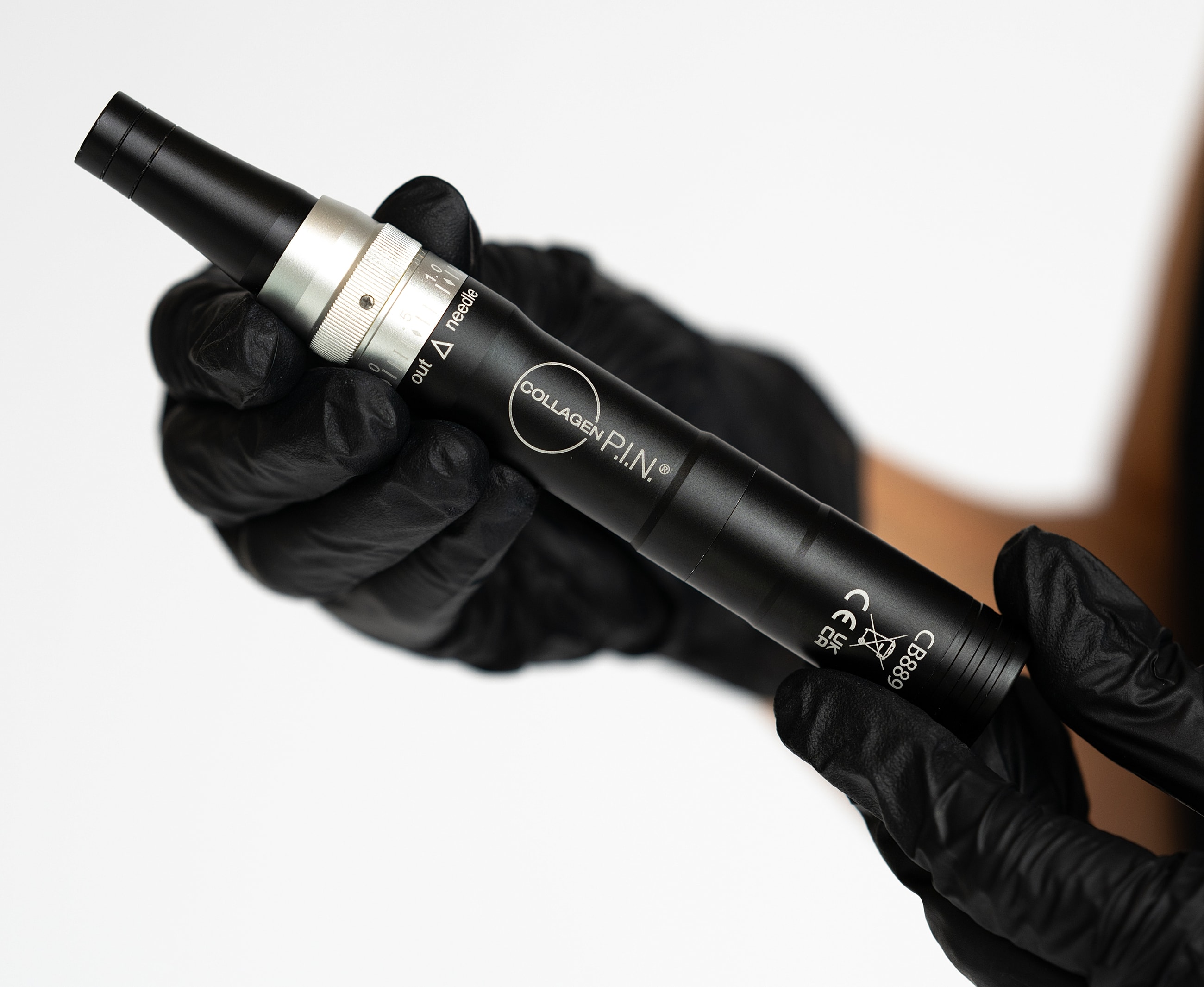 Collagen pen held in gloved hand.