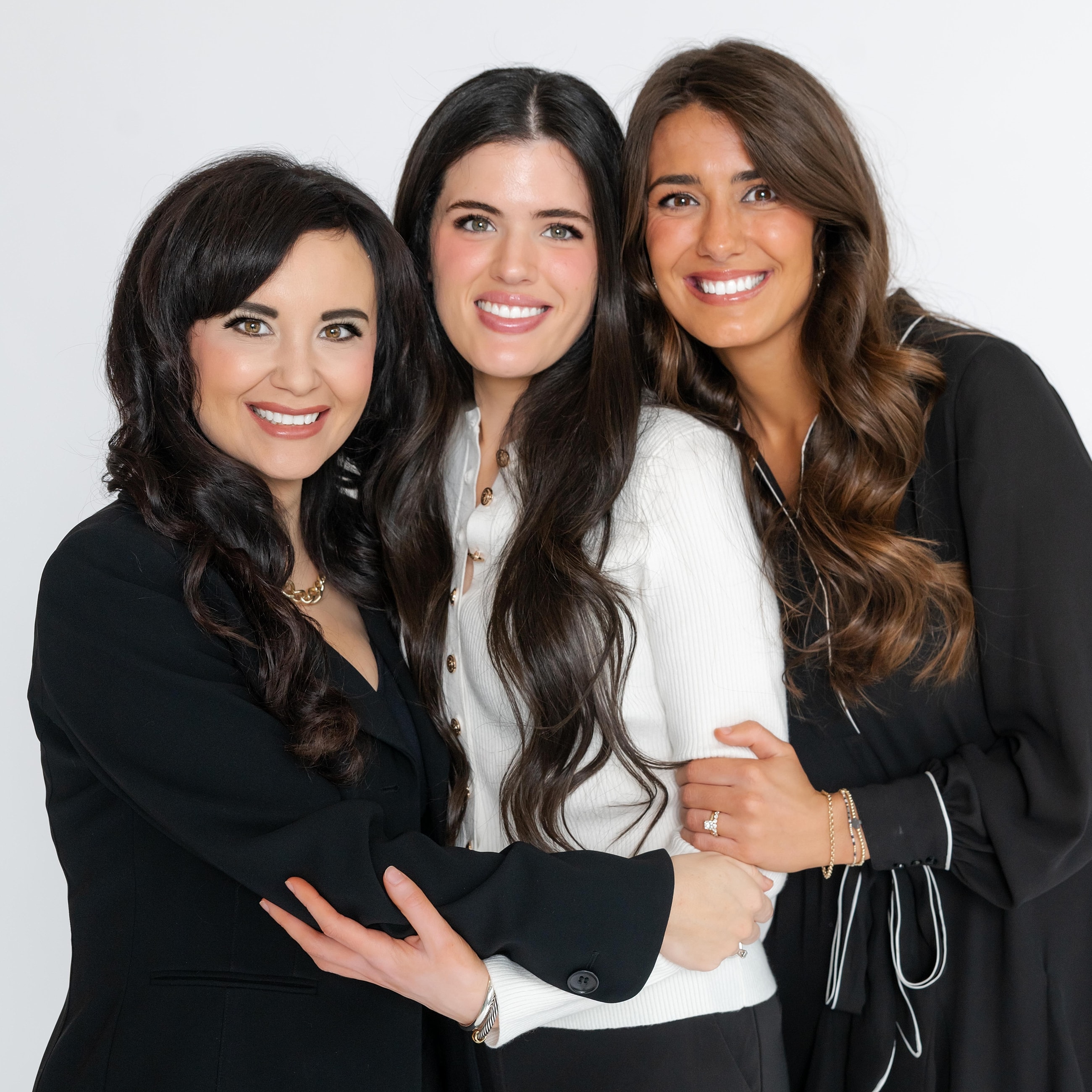 Three women smiling together in studio portrait.