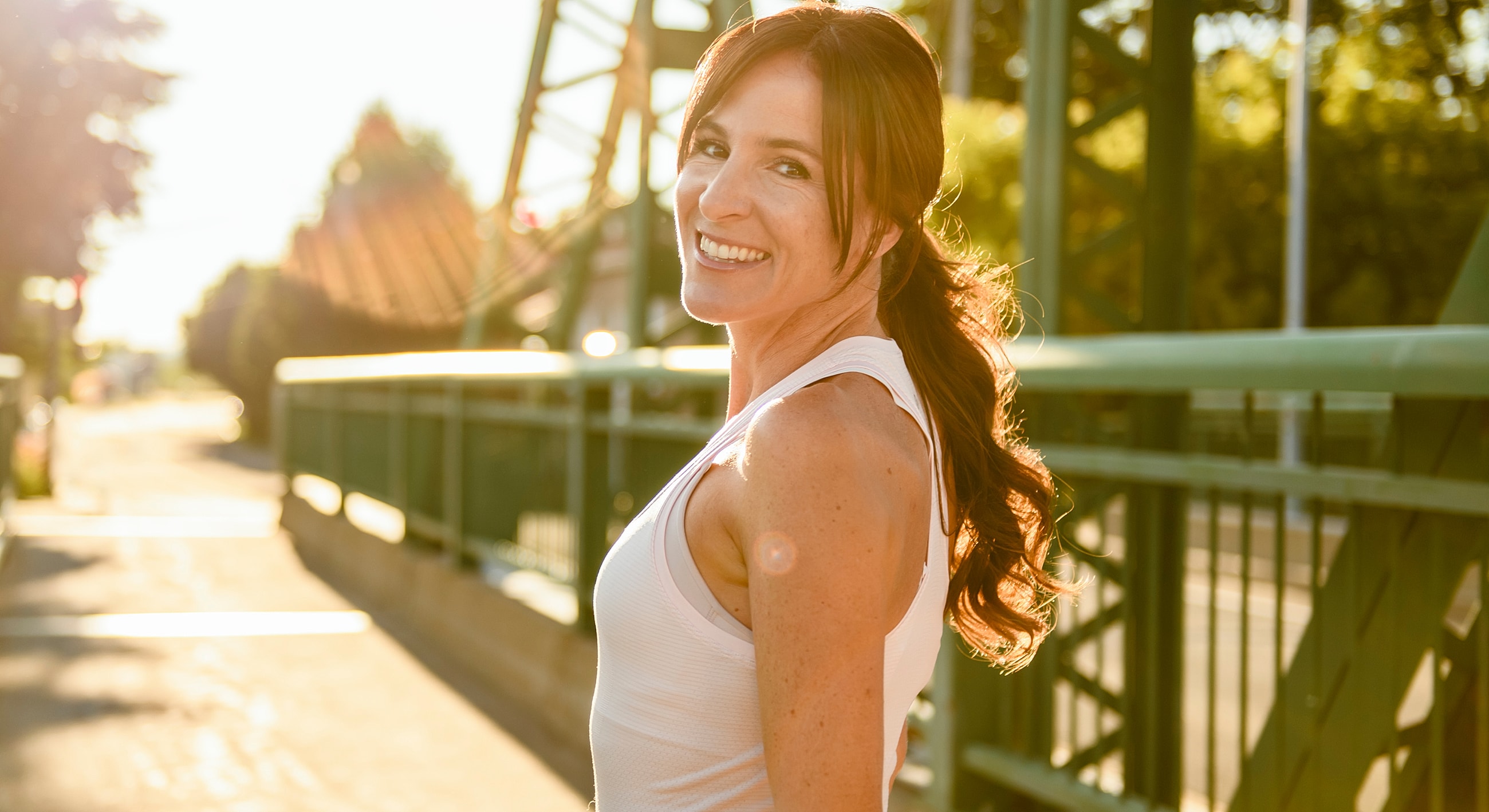 Smiling woman on a sunny bridge.
